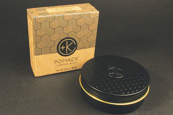 Small round black tin on black background next cardboard box that holds it