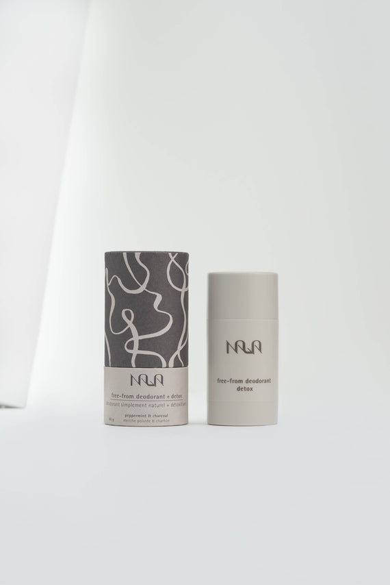 Light grey cylindrical natural deodorant tube sitting next to decorative a box