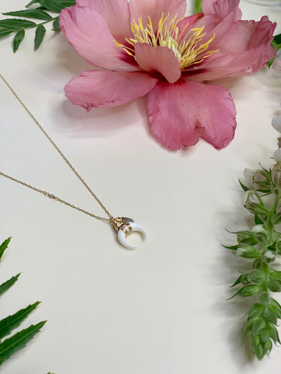 dainty gold chain with single cut in stone bead. hanging off of chain is a wire wrapped carved white horn of dilemma with a hanging wrapped bead as well