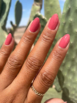 The nail polish on a medium skin toned hand in direct sunlight. The color looks saturated and blushy. 