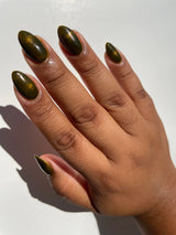 nail polish swatch on a medium skin tone hand colour is golden and reflective￼