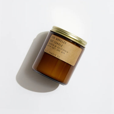 Amber glass jar with gold screw top of lid and brown paper label on a neutral background