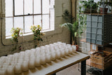 Table in a beautiful workshop covered in empty glass jars waiting to be filled with candlewax
