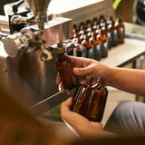 man filling amber glass bottles with liquid