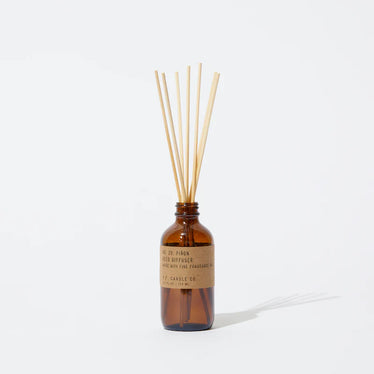 Amber glass jar with brown paper label holding wood reed sticks