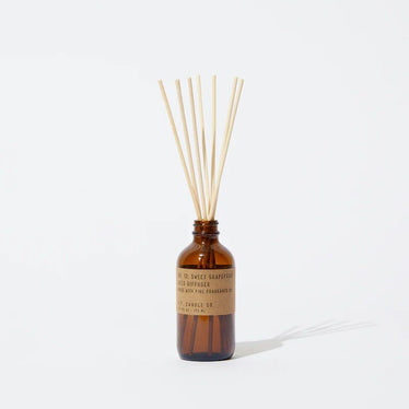 amber glass bottle with brown paper label holding reed diffuser sticks