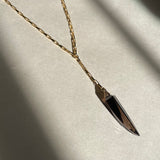 Necklace with a black dagger pendant on a light gray background