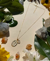 Detail shot of necklace shows Saint Mary pendant with small moonstone bead and dainty gold chain