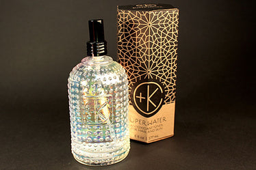 holographic glass decorative bottle with black spray nozzle sitting next to decorative box