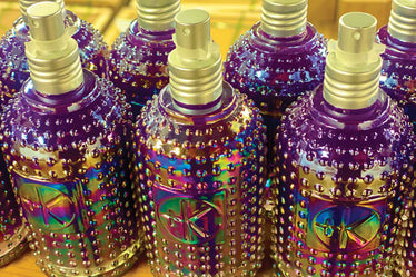 Glass purple holographic bottles with textured dots lined up next to each other