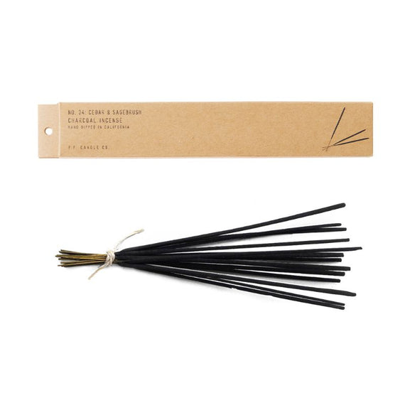 bundle of black incense sticks tied together with twine next to cardboard box that holds them