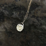 Details shot of pendant showing Roman coin stamped into metal