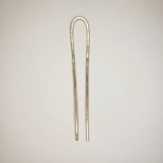 hand hammered brass hair pin, simple shape showing two prongs bent over at the top 