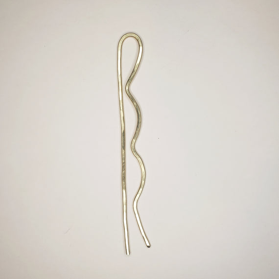 brass tone hammered hairpin on white background. the hairpin has two prongs. one with three bubble on the side to resemble a bobby pin