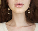 Woman wearing asymmetrical pearl earrings. The length hitting just below her chin. 