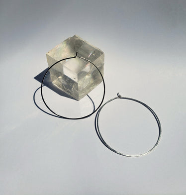 Two large circle hoops are neutral background one leaning against a cubic crystal