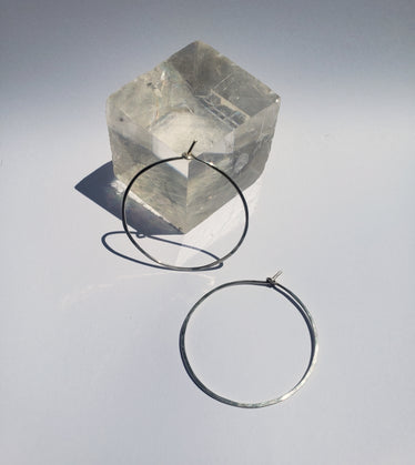 Small circle hoops on neutral background one hoop leaning against a crystal