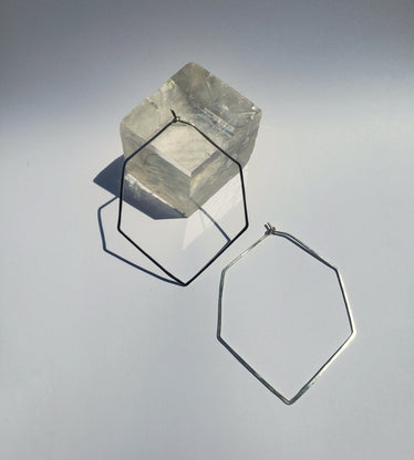 Two large hexagon hoops on white background one leaning up against a cubic crystal