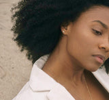 Woman looking down wearing the gold stud in her ear that looks similar to a lightening bolt. 