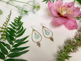 light blue stone earrings lay flat against white background with decorative flowers 