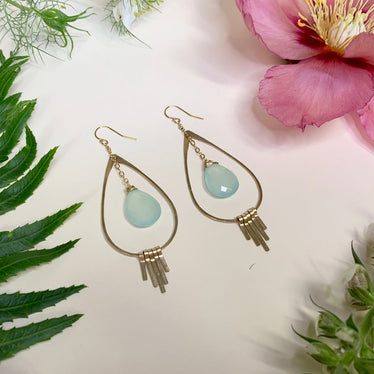 light blue stone earrings lay flat against white background with decorative flowers 