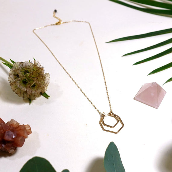double hexagon necklace laying flat on cream background with leaves and crystals￼