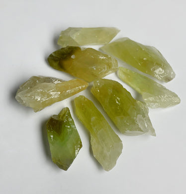 Small green calcite pieces on white background showing bright mossy green color