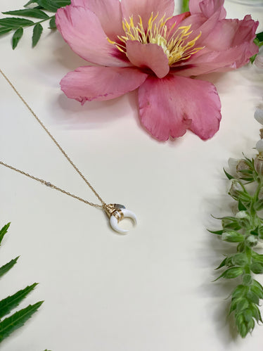 dainty gold chain with single cut in stone bead. hanging off of chain is a wire wrapped carved white horn of dilemma with a hanging wrapped bead as well 
