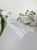 Small selenite sticks with decorative flowers on neutral background