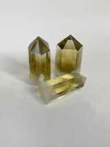 three citrine obelisks on a white background. two standing, one on its side. shows the clear yellow smokey tone of the crystal 