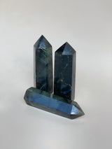 Two labradorite obelisks standing up, one on its side all on a neutral background