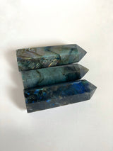 three labradorite obelisks laying on their side with light bouncing off showing all of the different coloured flash￼