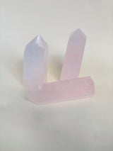 Two rose quartz obelisk standing straight up one on its side showing light refractions