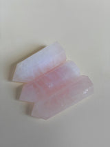 Close-up shot of three rose quartz obelisks laying down showing deep pink hues and white striations