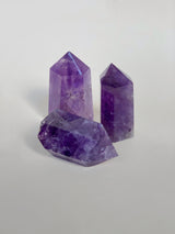 Three purple amethyst obelisk. two standing. one on its side. 
