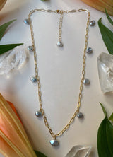 Gold paperclip chain necklace with nine silver blue toned pearls scattered evenly throughout￼