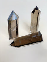 Too smoky quartz obelisks standing up one on its side showing light refraction