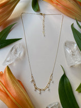 flat lay image of the mini pearl chain necklace laying on a white background surrounded by crystals and flowers￼
