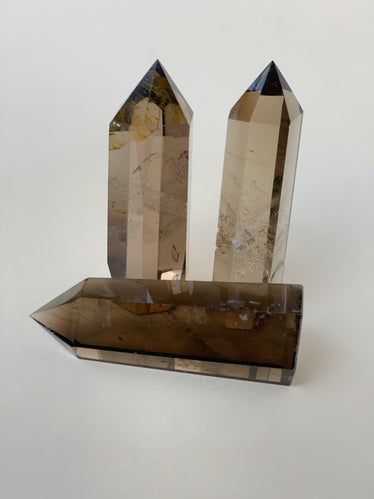 Three smoky quartz obelisks on neutral background