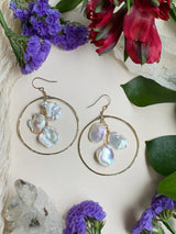 two gold earrings highlighting three freshwater pearls encapsulated by a hammered gold hoop￼