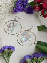 freshwater pearl hammered hoops laying on a white background surrounded by flowers￼