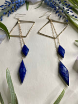 Double diamond drop earrings in lapis and gold laying flat on cream background