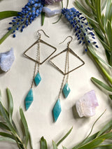 two earrings featuring horizontal diamond shapes with two diamond shaped stones of amazonite hanging off of gold chains from the top of the earring