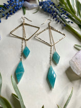 two earrings featuring horizontal diamond shapes with two diamond shaped stones of amazonite hanging off of gold chains from the top of the earring