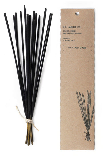A bundle of black incense sticks tied with twine and a cardboard box that holds them with black text 