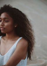 Woman looking into distance wearing either studs the gold tone shines bright