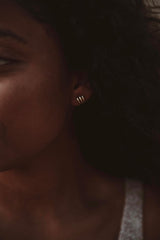 Close-up of Ira earrings on woman’s ear studs almost appear to look like three hoops because of the line is coming down over the ear lobe