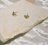 Golden studs on stone with satin background the studs resemble claws with three sharp lines￼