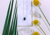 Necklace on white tile with flowers showing the scale and size of chain and geode proportions