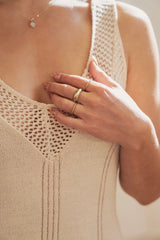Woman with hand on chest wearing multiple rings featuring in the middle the Iona ring￼